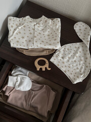 Clothes and accessories for a newborn baby are on the bedside table and in the drawer. Waiting for a miracle. Children's accessories