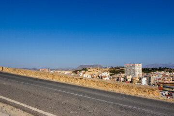 Panoramic view of Alicante, Spain, showcasing a cityscape with buildings and distant mountains under a clear blue sky. Ideal for travel and architecture themes.