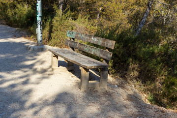 A weathered wooden bench sits along a gravel path surrounded by lush greenery, inviting relaxation...