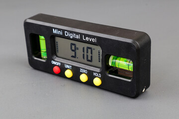 Mini digital level. Professional digital tool inclinometer isolated on grey background for leveling and inclination measurements.