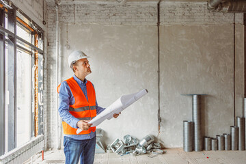 Construction worker analyzes blueprints in a newly built office space during daylight hours