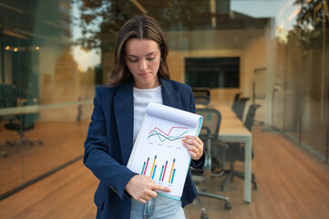 Businesswoman showing and pointing at charts and graphs on a notebook