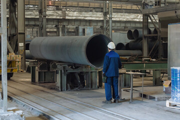 Worker examines new cast iron pipe in factory