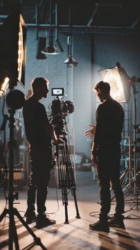 Film crew team with light man and cameraman working together with director in big studio, video production