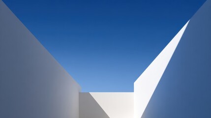 White architectural walls forming geometric pattern against vivid blue sky, casting crisp shadows highlighting clean lines and minimalist architectural design