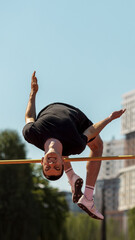 Athlete midair executing high jump at outdoor track and field event. Concept of elite training...