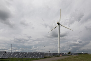 Wind turbine and solar panels renewable energy farm under cloudy sky