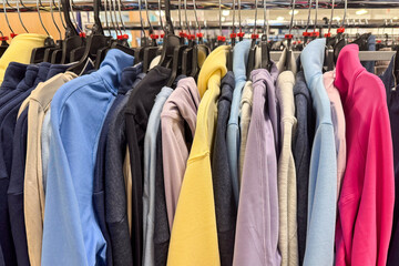 A tightly packed clothing rack displays a colorful assortment of sweatshirts and hoodies