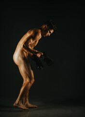 A dark and moody artistic photograph of a male model posing gracefully under creative lighting,...