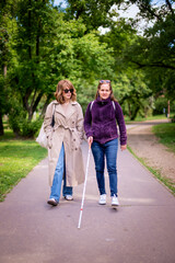 Visually impaired woman walking with her female friend at city park