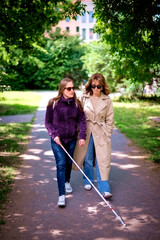 Visually impaired woman walking with her female friend at city park