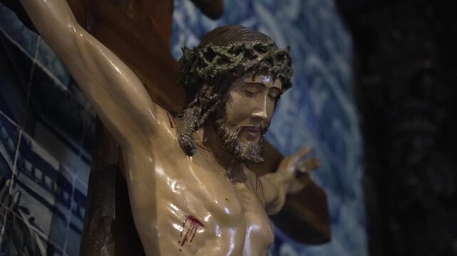 close up of jesus on cross statue with crown and wounds inside chapel