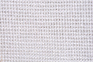 A close-up of white tapestry fabric texture with a visible square weave pattern