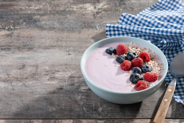 Healthy smoothie bowl with berries on wooden table. Copy space