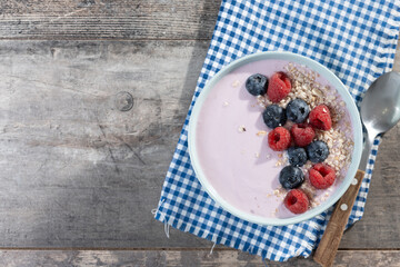 Healthy smoothie bowl with berries on wooden table. Top view. Copy space