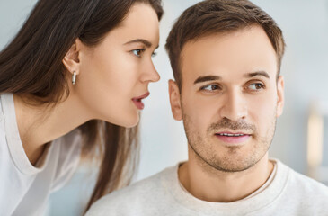 Chatty woman, talkative wife telling secret to man, husband, whispering at ear, family chatting,...