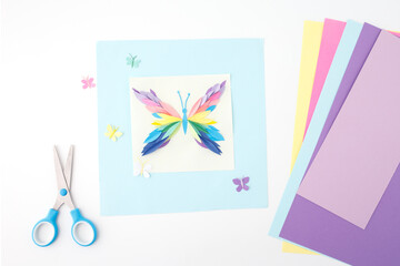 cheerful and crafty moment centered around a handmade paper butterfly. Sheets of colored paper to the sides in tones of blue, pink, green, and purple. joyful DIY session,