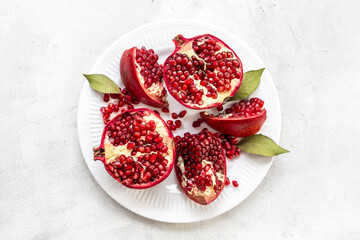 Top view of fresh ripe pomegranate and pieces on plate for eating, top view.
