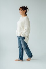 Confident mature woman walking barefoot in studio, embracing casual style