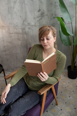 Woman reading a book while relaxing in an armchair