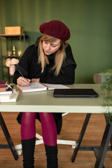 Woman artist sketching in notebook at home office desk