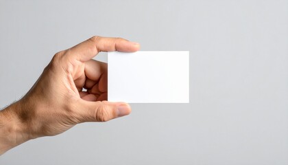 Obraz premium Mano de hombre sosteniendo una tarjeta blanca sobre fondo gris. 