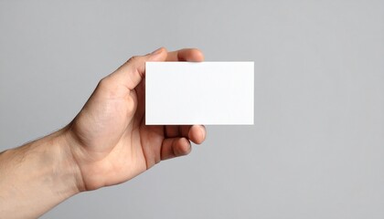 Mano de hombre sosteniendo una tarjeta blanca sobre fondo gris.
