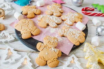 Christmas gingerbread cookies in the shape of a snowman on a white wooden background. Christmas decorations. Top view, flat lay.