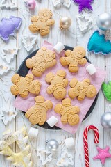 Christmas gingerbread cookies in the shape of a snowman on a white wooden background. Christmas decorations. Top view, flat lay.