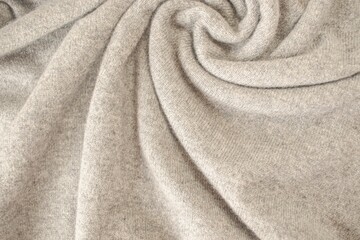 Cashmere beige fabric, top view. Draped, texture, background. Natural wool clothing.