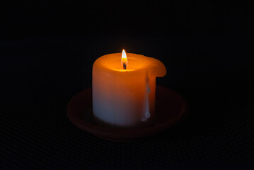 A burning candle in the darkness. Selective focus,black background.