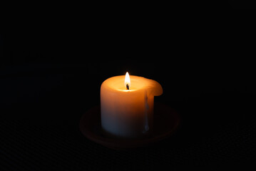 A burning candle in the darkness. Selective focus,black background.
