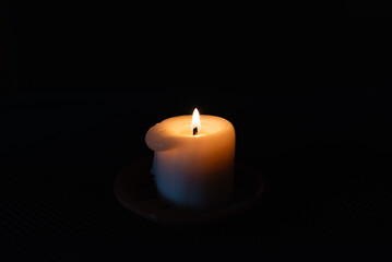 A burning candle in the darkness. Selective focus,black background.