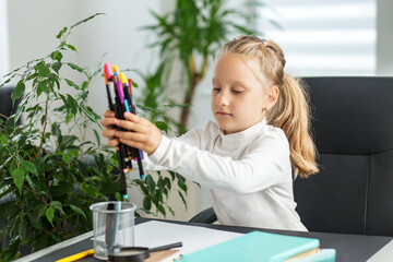 Focused child organizing colorful pens at desk
