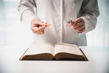 During the holy communion ceremony in church, a hand is extended in faith to receive the sacred...