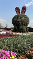 Easter bunny in the garden with flowerbeds and colorful flowers at Maple garden, popular attraction...