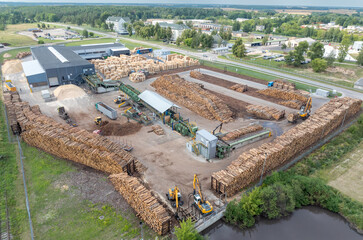 Wood sawmill, machinery for processing wood. Processing plant. A worker operating loader, modern wood processing factory, load freshly cut logs onto the production line for processing, manufacturing.
