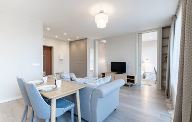 Living Room and Dinning Table. Sofa. Composition of Kitchen and Living Room Interior with Gray Sofa, Dinnig Table, Curtains, Accessories, Widows. Home decor. Watch on the Wall and TV Screen