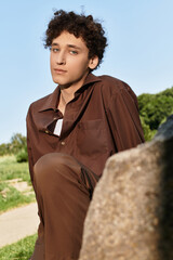 Young man enjoys a sunny day in green park wearing a stylish summer outfit