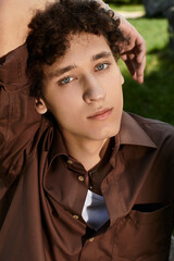 Curly-haired young man enjoying a sunny day in a vibrant green park setting