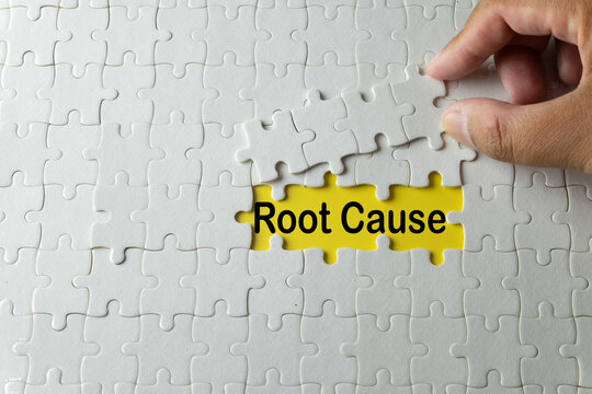 and putting the last piece of a white jigsaw puzzle to reveal the words Root Cause. A business concept of problem-solving, discovering the main issue, and root cause analysis (RCA).