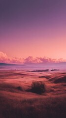 Fototapeta premium A serene landscape featuring a vast field with rolling hills under a pink and purple sky, showcasing nature's beauty and tranquility, perfect for scenic backgrounds.
