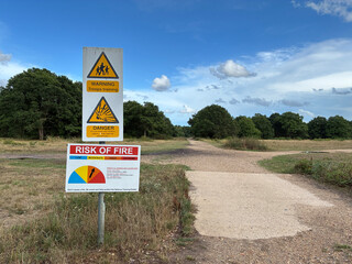 Warning signs reading 'Troops Training' and 'Risk of Fire' alert posted along woodland paths. Rural...