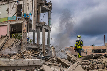 Fototapeta premium Firefighter standing on ruins of missile-struck building