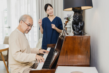 Asian young woman teaching piano for senior man teaching, happy daughter and elderly father playing...