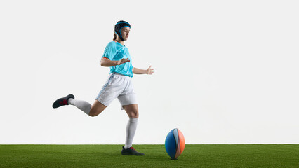 Female rugby player striking a ball on grassy field with dynamic movement. Concept of field play,...