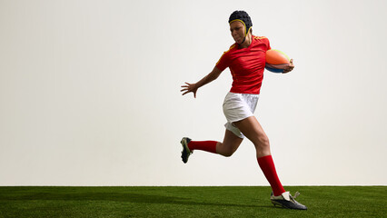 Female rugby player running with ball against white background. Concept of field movement, isolated dynamic, athletic style, player in motion and powerful stride