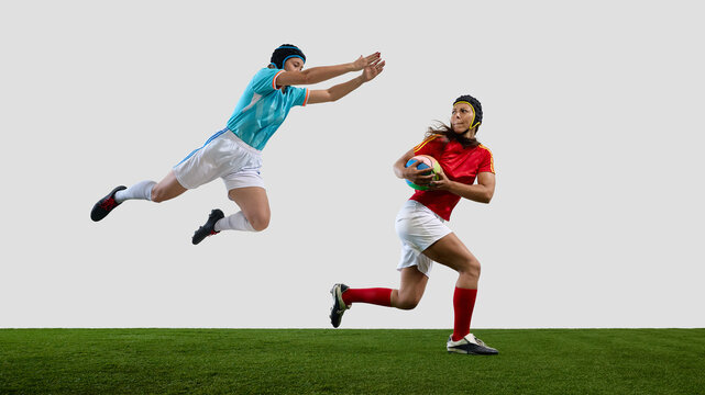 Dynamic rugby match with female athletes in action on field. Concept of tackle attempt, competition clash, fast pursuit, rugby intensity and field interaction
