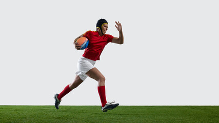 A female rugby player sprints across a grassy field dressed in her uniform, clutching a rugby ball, with resolve visible in her eyes. Concept of confident stride, athlete in charge, possession run