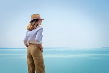 Rear view of a woman standing by the sea and enjoying the view